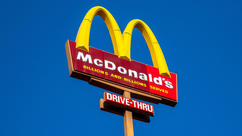 Golden arches McDonald's drive-thru sign against a blue sky