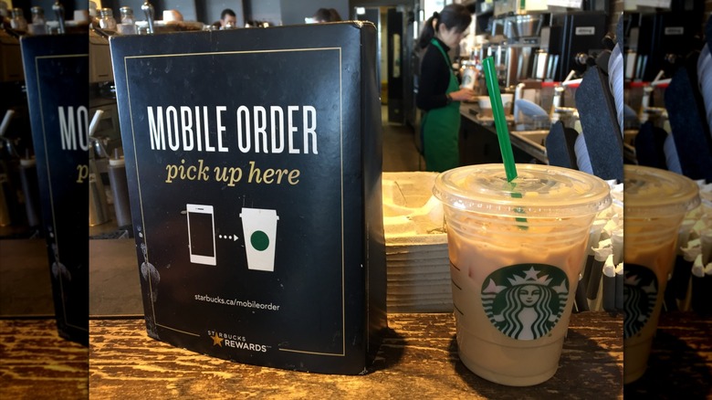 A Starbucks iced drink sits on a counter next to a sign that says, "Mobile order, pick up here."