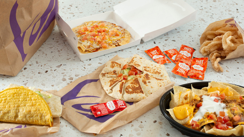 A spread of Taco Bell items with hot sauce packets arranged on a granite table