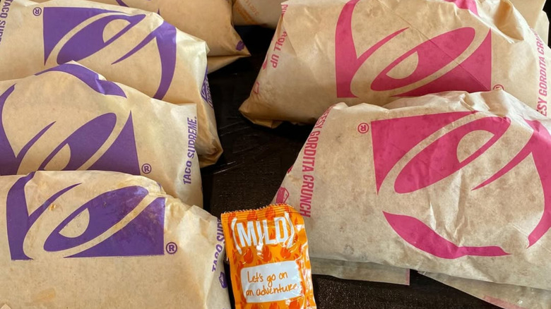 Taco Bell items wrapped in brown branded paper with a mild hot sauce packet
