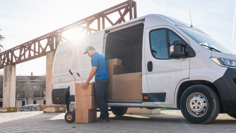 Delivery driver unloading packages from van