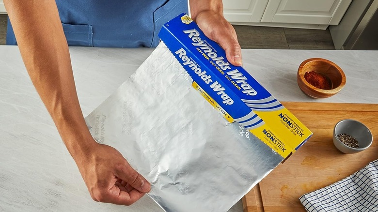 Person pulling aluminum foil out of a yellow-coded Reynolds Wrap box