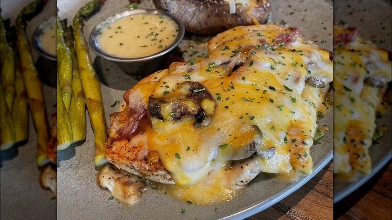 Outback Steakhouse Alice Springs Chicken on plate beside a sauce, potato, and asparagus