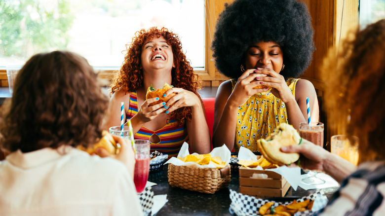 Friends eating burgers in a restaurant