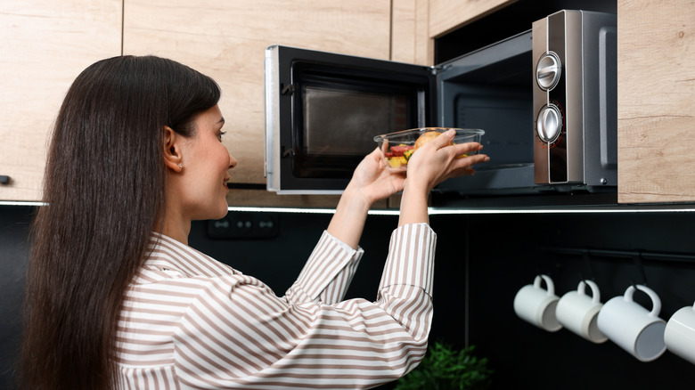 Woman placing glass dish into microwave
