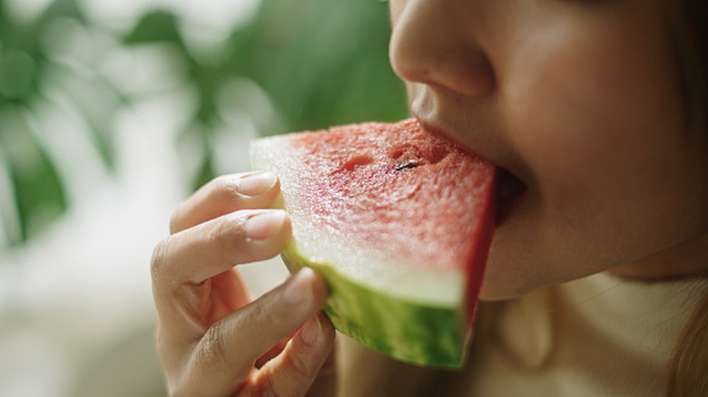person eating slice of watermelon