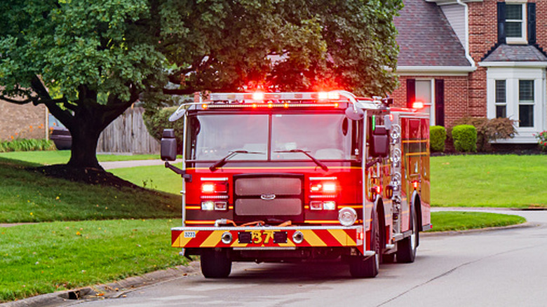 A firetruck with its emergency lights turned on, in a suburban neighborhood