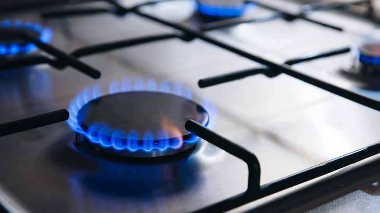 Turned on gas stove burner with a blue flame.