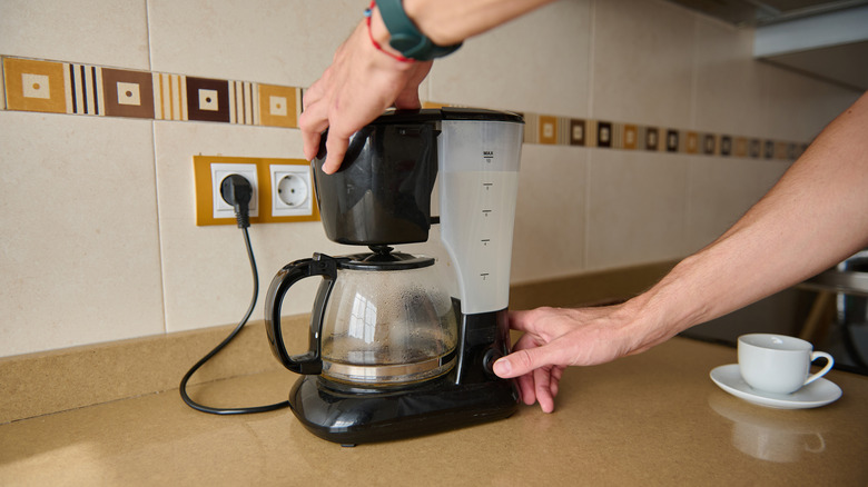 Person using a drip coffee maker at home