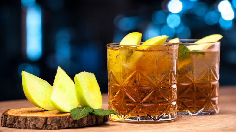 Two apple whiskey cocktails with sliced apples