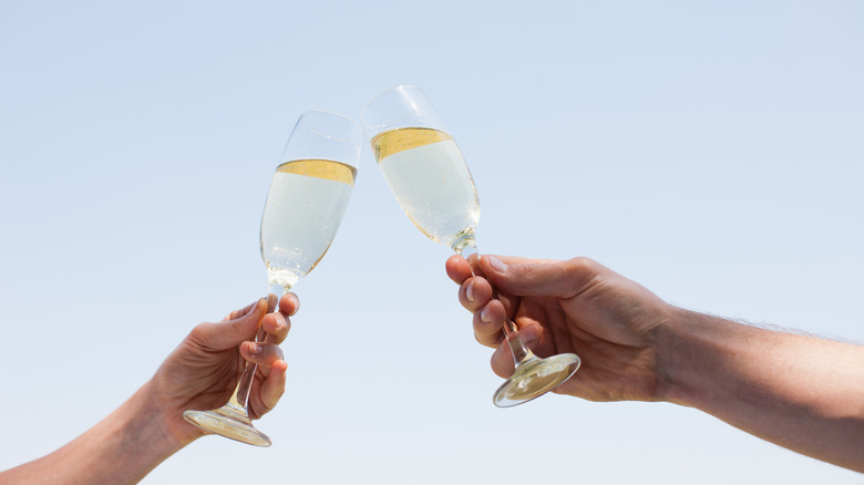 Two people toasting with flutes of sparkling wine