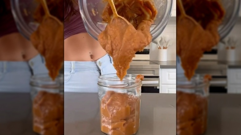 Spooning date paste from blender into glass jar