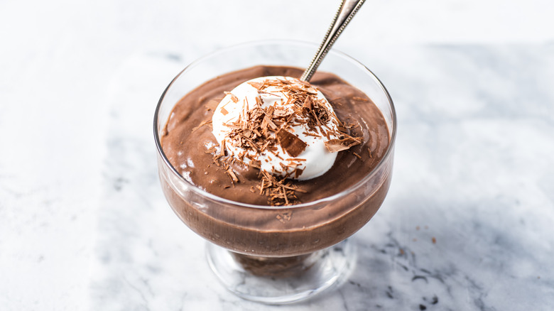 Chocolate mousse in glass ramekin, topped with coconut cream and chocolate shavings