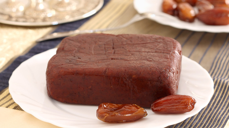 Block of date paste on white plate with whole dates