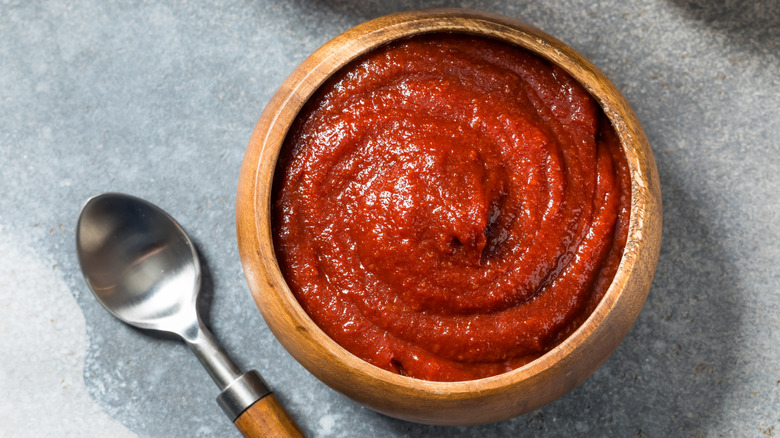 Gochujang paste in a wooden bowl with a wooden-handled spoon