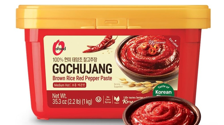 Plastic container of Chung Jung gochujang paste with a small bowl of gochujang in front