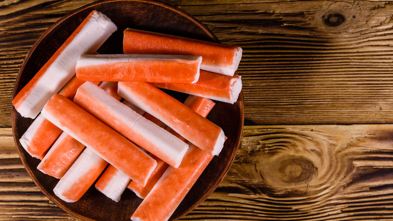 Imitation crab sticks on brown plate on wooden table