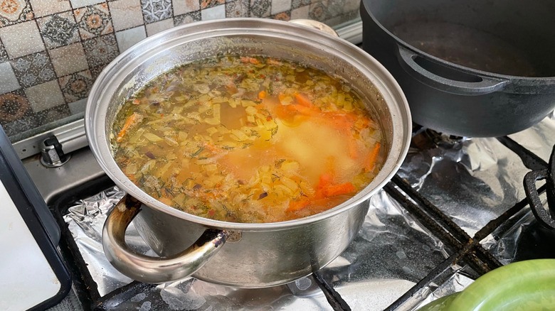 onions and carrots simmer in a pot on the stove