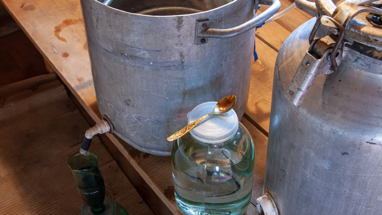 Jar of moonshine by distilling equipment