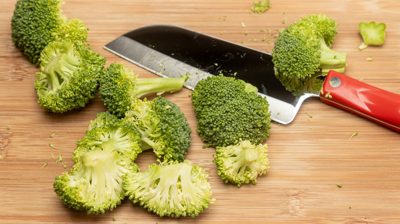 Santoku knife with chopped broccoli on cutting board
