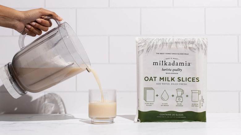 Milkadamia oat milk package next to person pouring milk from blender into glass