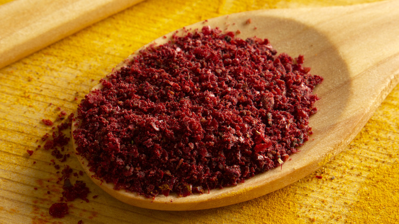 Sumac in wooden spoon on yellow background