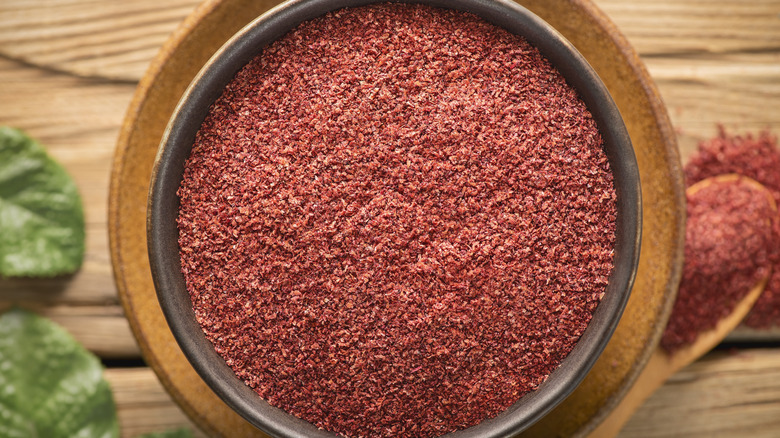 Sumac in brown bowl on wooden table