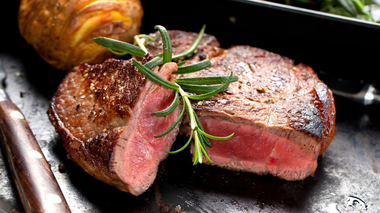 Steak cut open on a plate and garnished with a sprig of rosemary