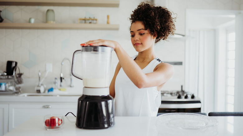 Foodie using an electric blender in a modern home kitchen