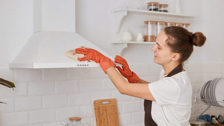 Person cleaning the range hood in a home kitchen
