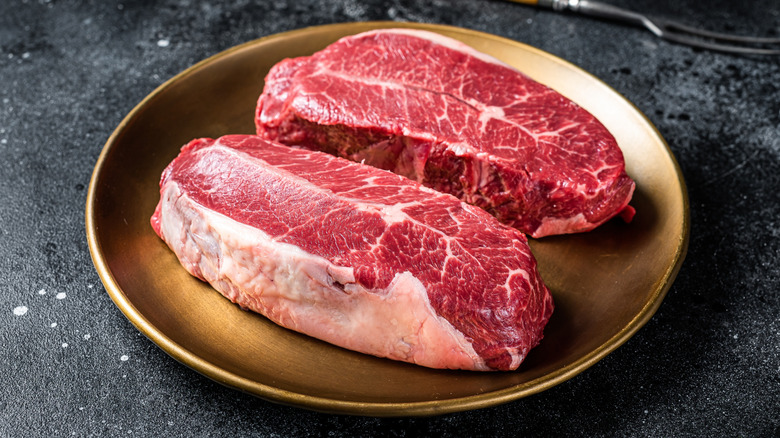 Two pieces of well-marbled steak on a golden plate
