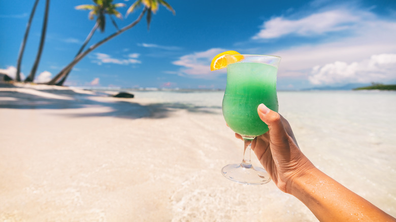 a person holding a frozen cocktail at the beach