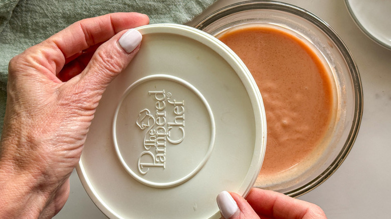 Placing lid on glass container of yum yum sauce