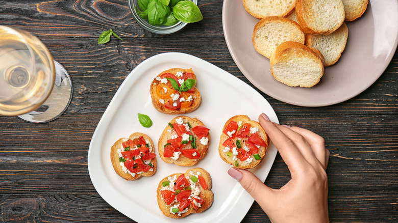 Hand reaching for tomato canape