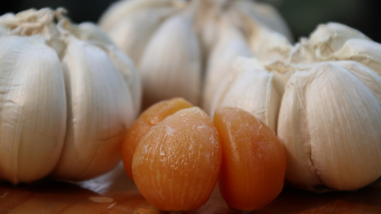 Orange cloves of garlic surrounded by fresh bulbs