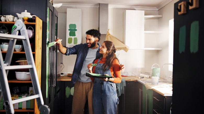 Happy couple paints the cabinets in their kitchen