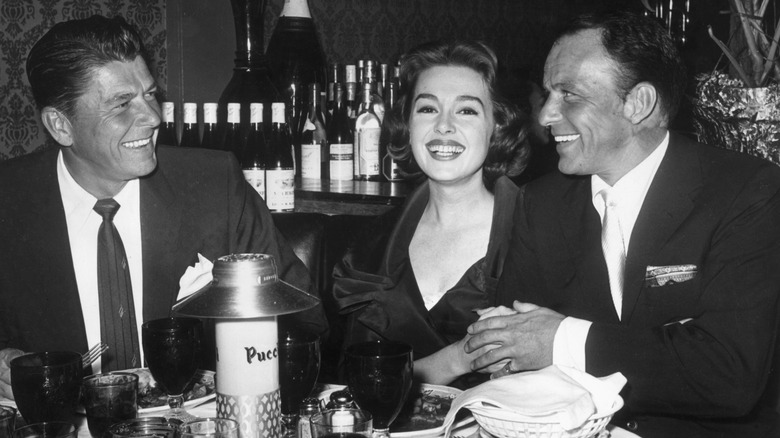 Black-and-white photo of Frank Sinatra and the Reagans sitting at a dinner party table