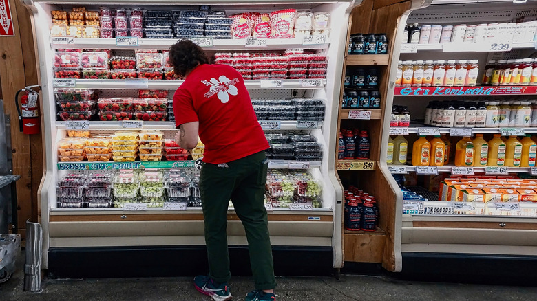 Trader Joe's employee stocking shelves with packaged fruit