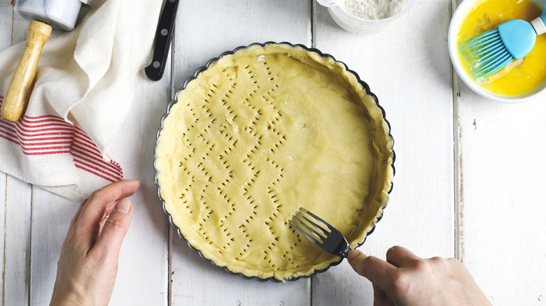 Person poking holes in pie crust using a fork