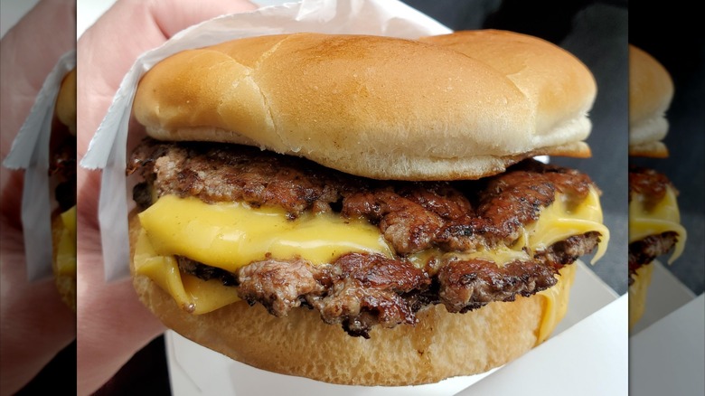 Close up of someone holding a fresh ButterBurger with the beef patties accentuated.