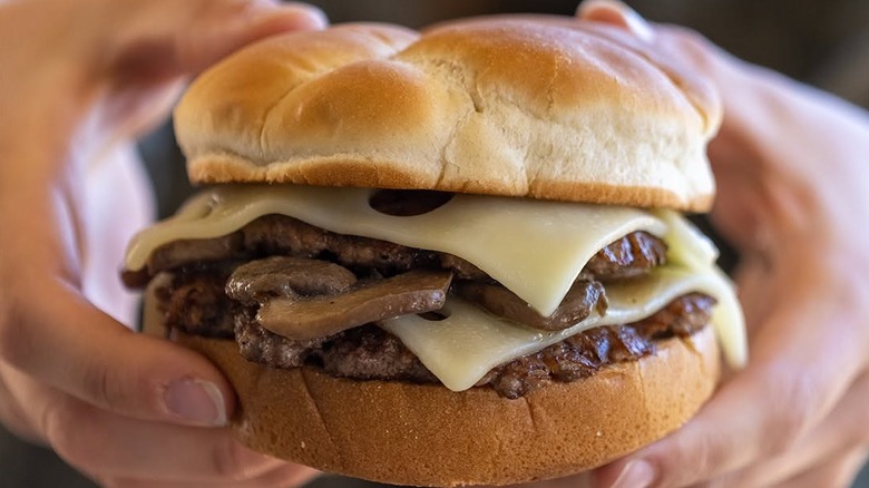 Close up of someone holding a Culver's Mushroom and Swiss ButterBurger.