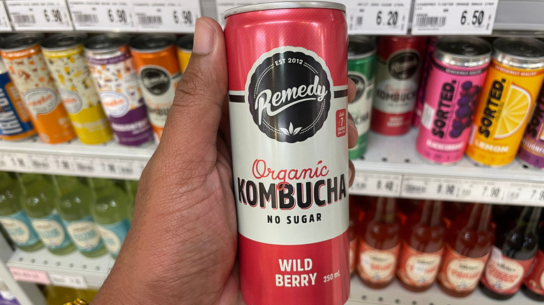 Hand holding can of Liquid Remedy kombucha in supermarket