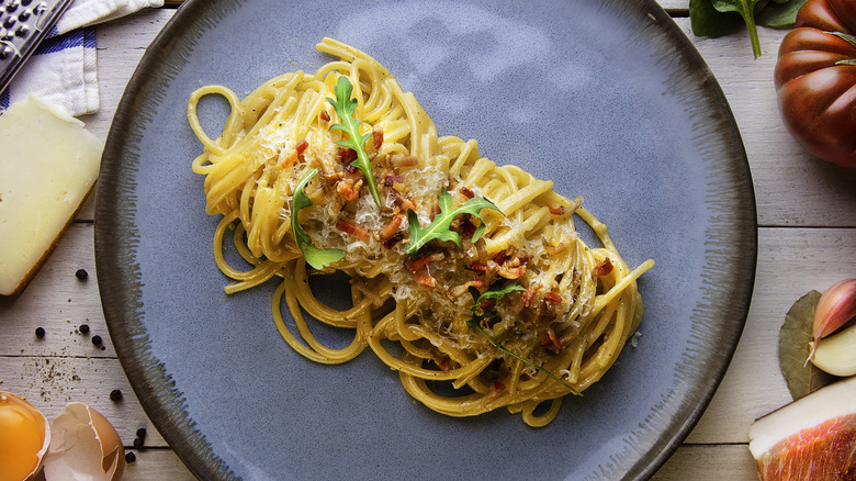 plate of spaghetti alla carbonara with ingredients on the side
