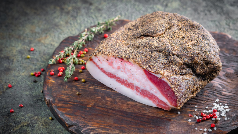 cured pork jowl covered in spices on a wooden board