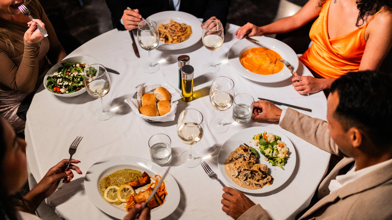 A group of adults eating entrees at a circular table