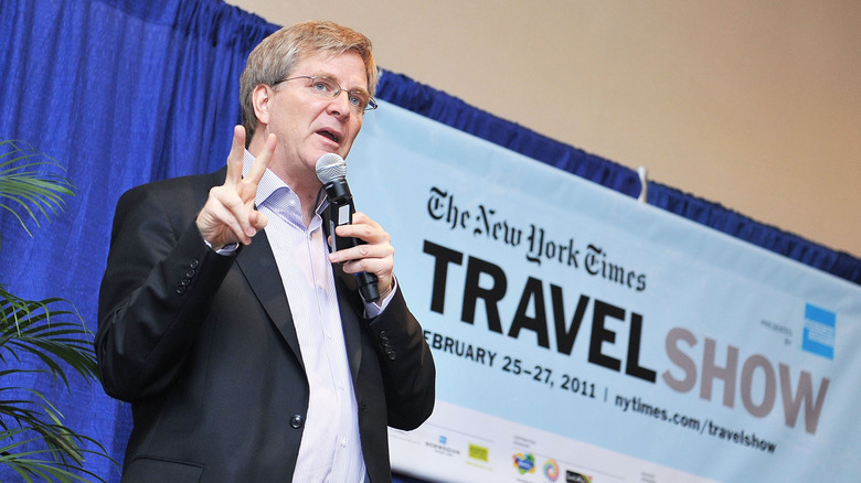 Rick Steves holding microphone speaking at New York Times Travel Show