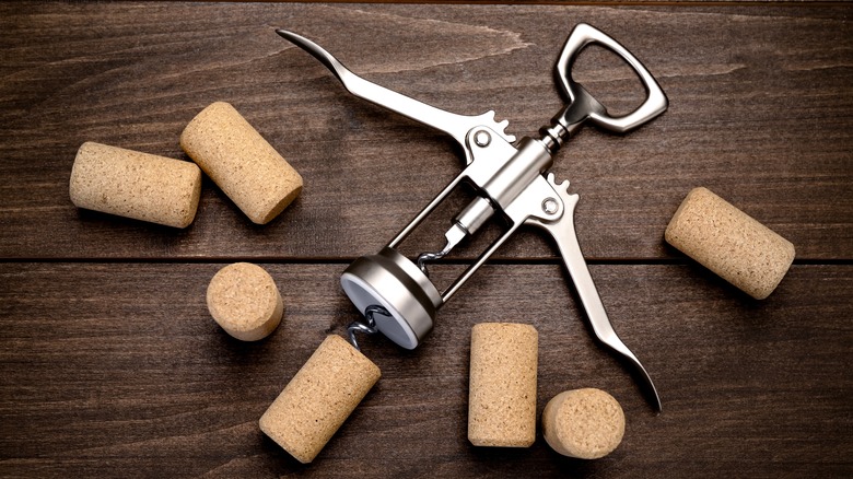 A winged corkscrew and several corks lying on a table