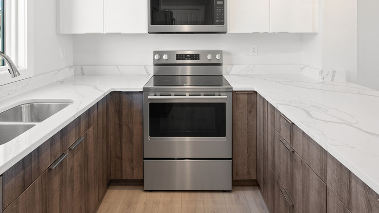 An oven sits between gray kitchen cabinets