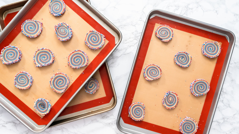 Spiral cookies sit on silicone baking mats on cookie sheets