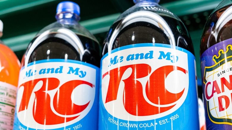 Two blue, white, and red labeled bottles of RC Cola on a store shelf